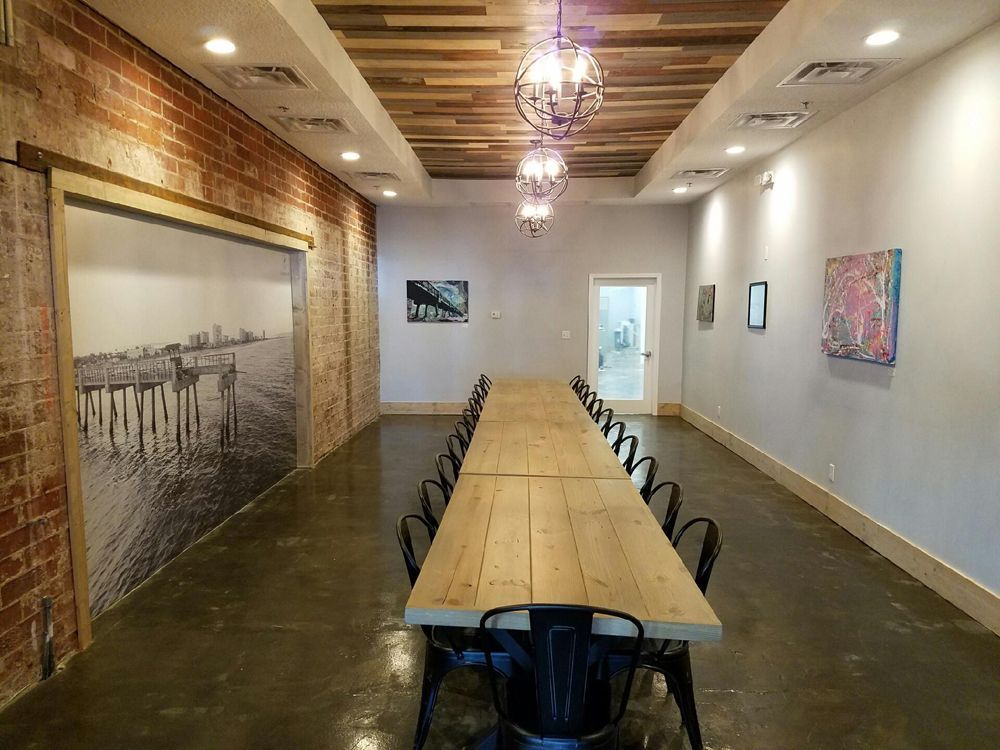 Long conference table with chairs in a room with brick walls, art, and a decorative ceiling.