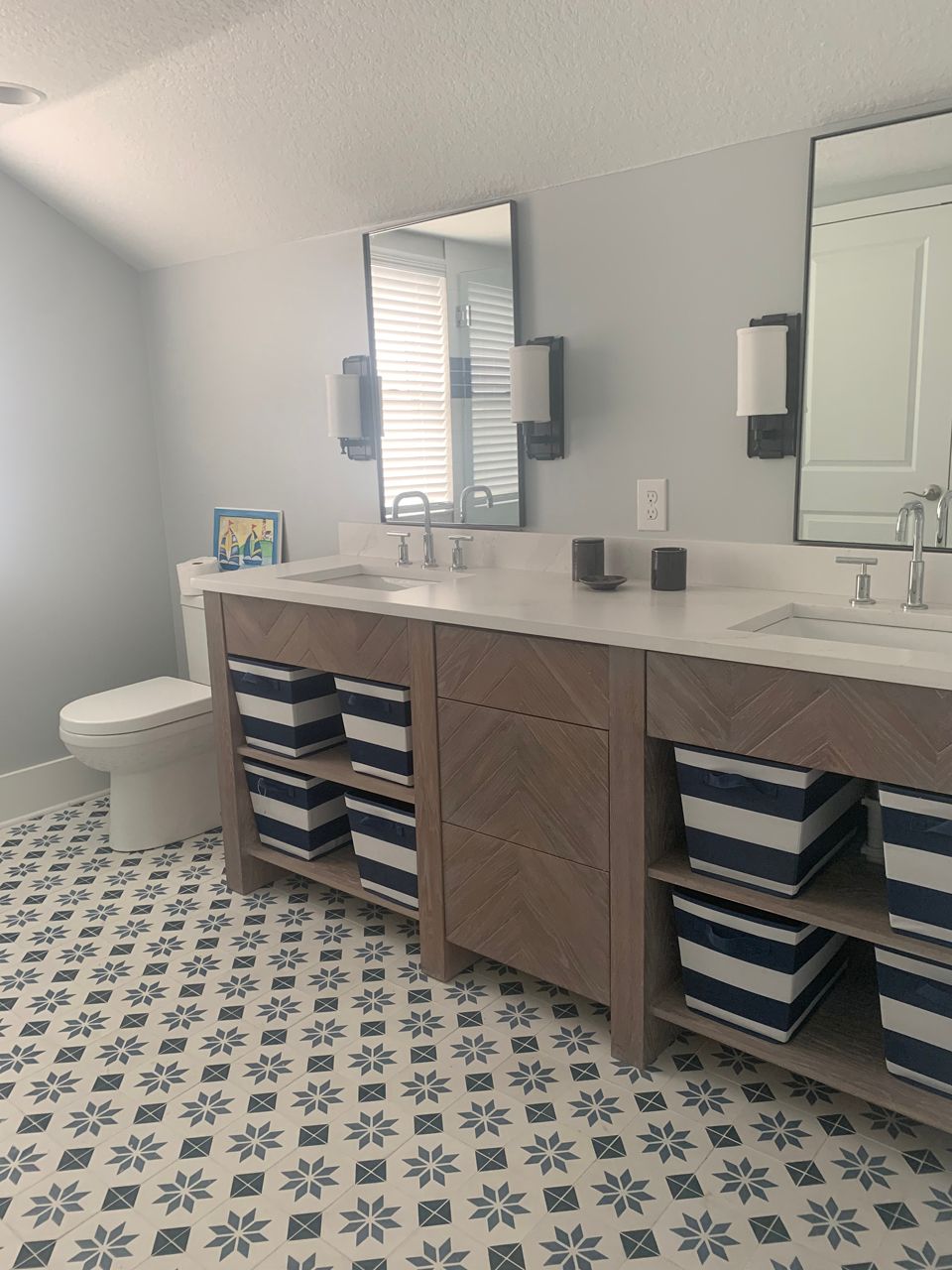 Bathroom with double sinks, blue and white patterned floor, and storage bins.