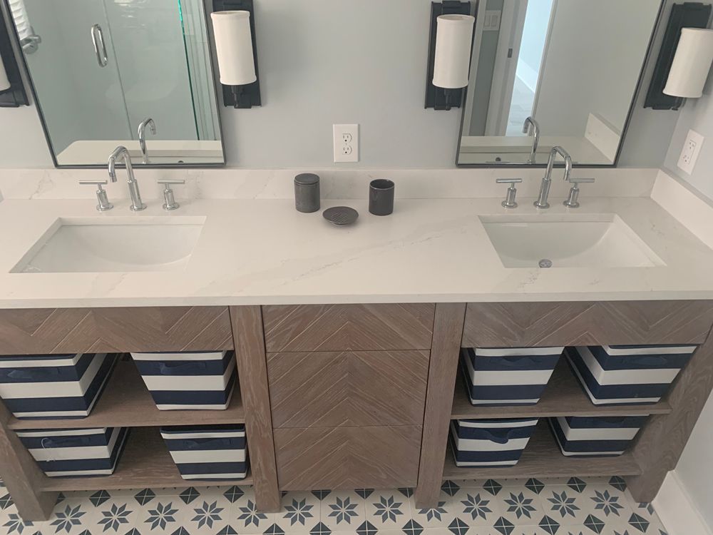 Bathroom vanity with two sinks, gray countertop, and storage baskets with blue stripes.