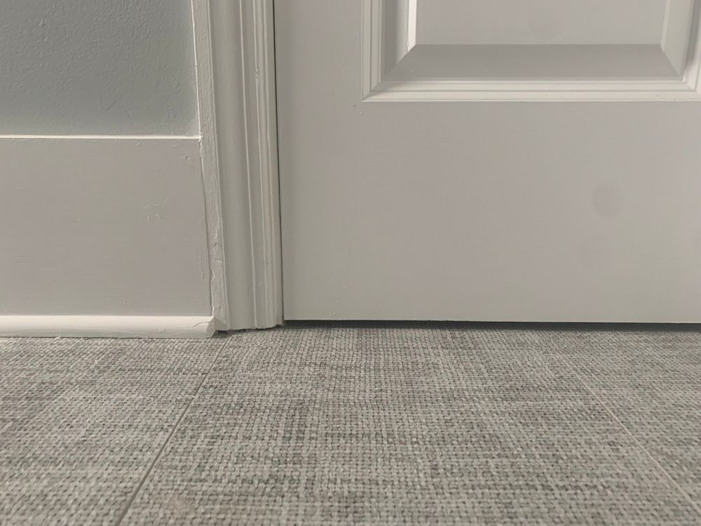 White door and trim next to gray textured flooring.