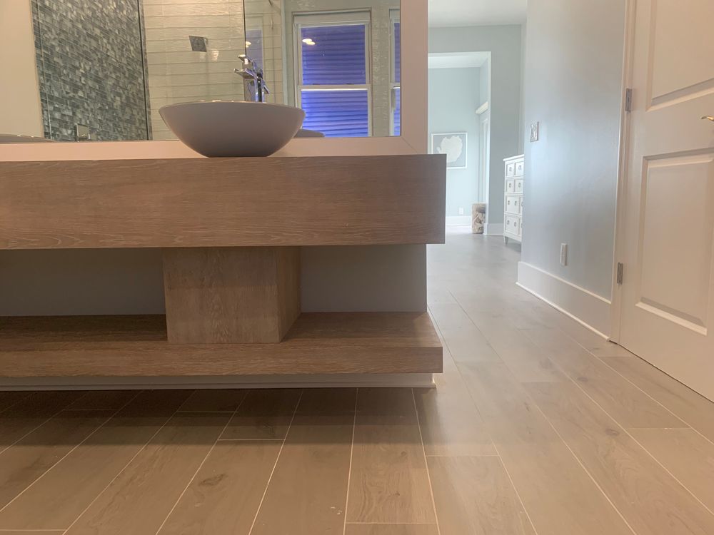 Bathroom with wooden vanity, gray sink, and light wood floor.