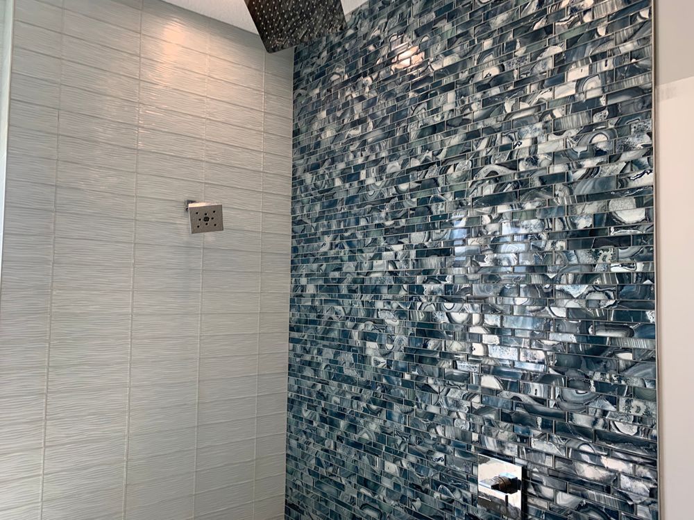Shower with blue mosaic accent wall and gray tile.