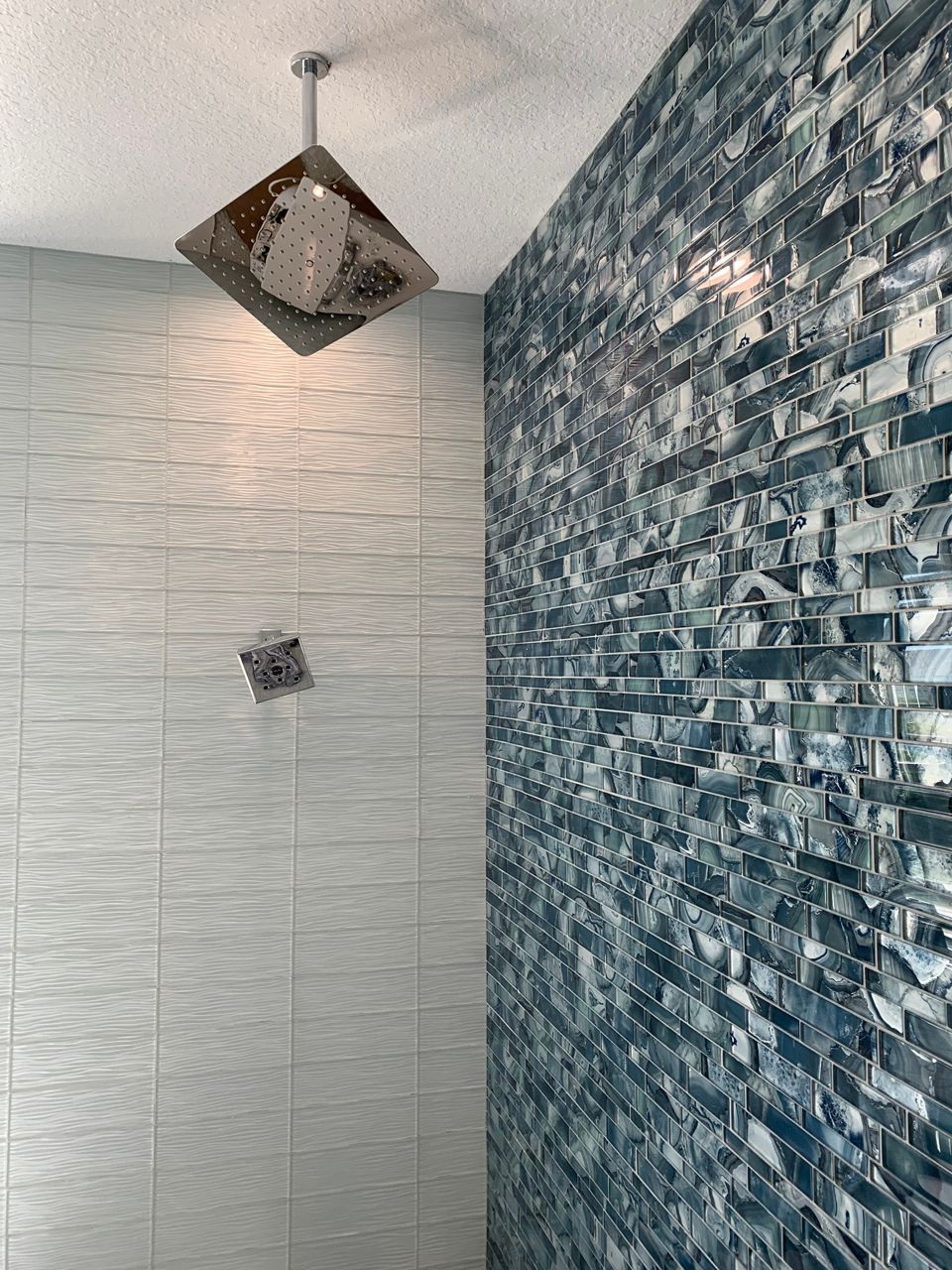 Shower with blue tile accent wall and overhead square shower head.