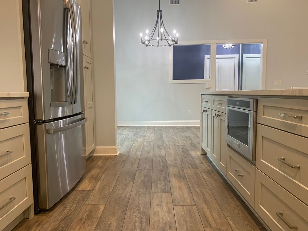 Kitchen with light cabinets, stainless steel fridge, and hardwood floors. View of dining room.
