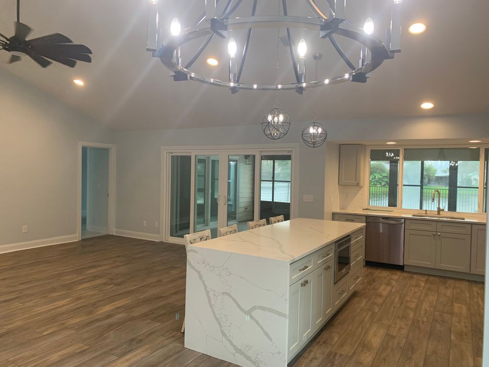 Spacious kitchen with an island, large windows, and a modern chandelier.