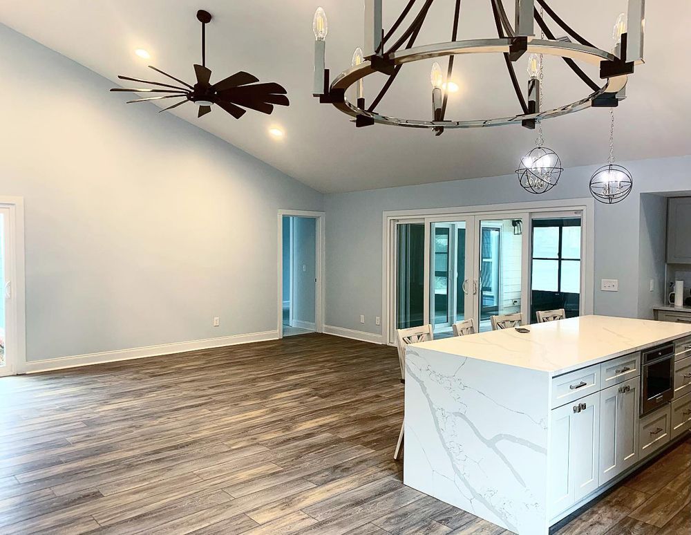 Open-concept living space with light blue walls, wood floors, and kitchen island with two pendant lights.