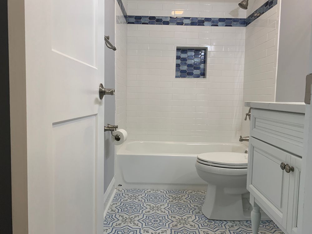 Bathroom with blue and white tiles, white fixtures, and a partially visible door.