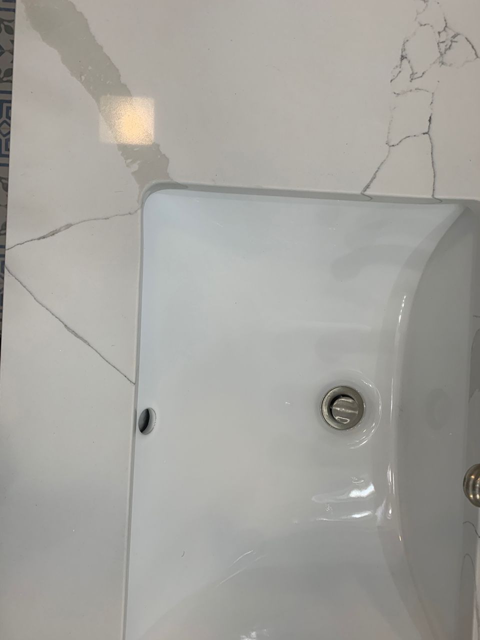 White bathroom sink against a white marble wall.