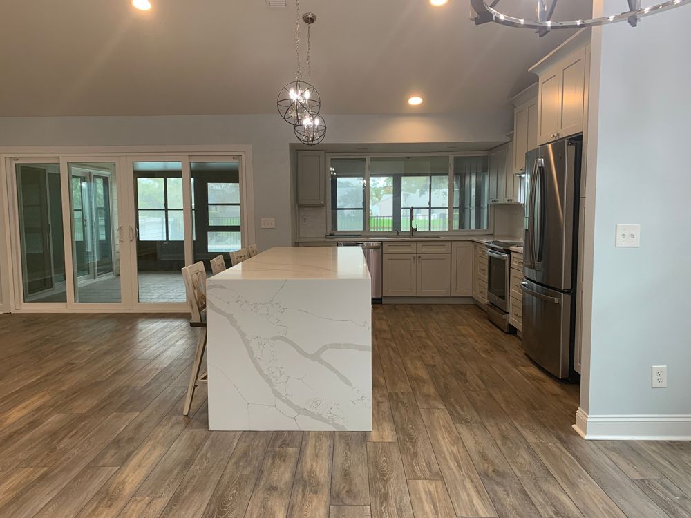Modern kitchen with a white island, stainless steel appliances, and sliding glass doors.