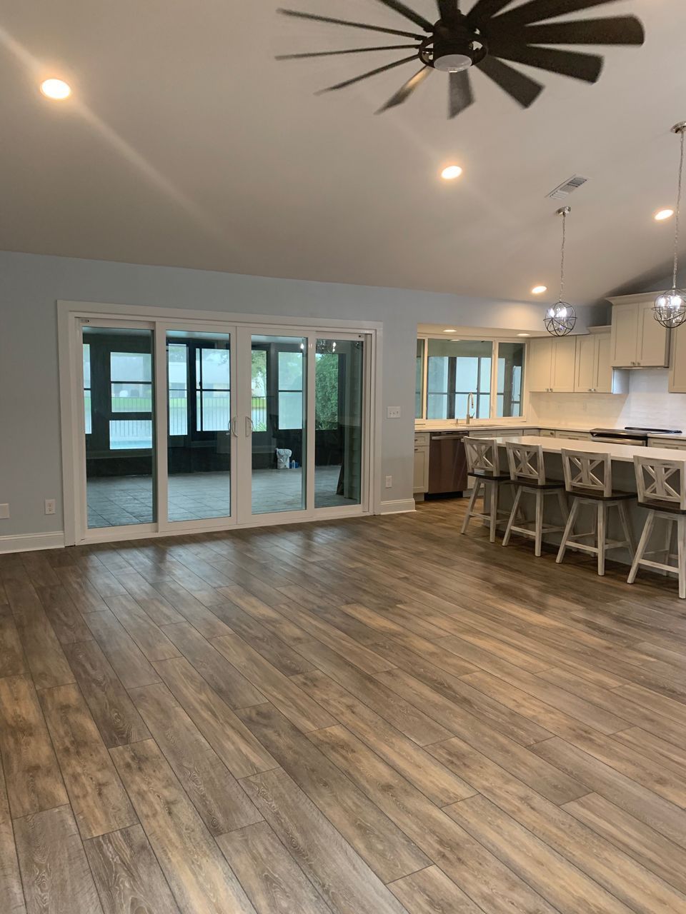 Open-plan living space with wood floors, sliding doors to a sunroom, and a kitchen with a large island.