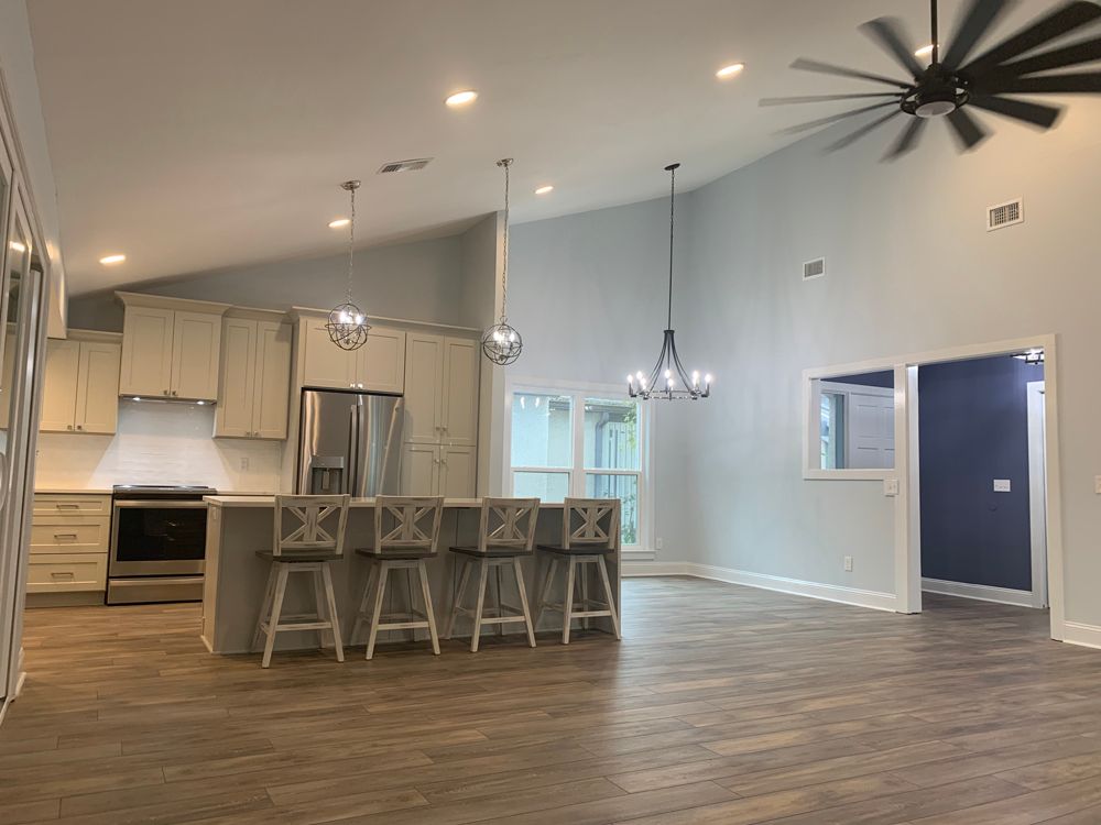 Kitchen with light cabinets, stainless steel refrigerator, island with a white countertop.