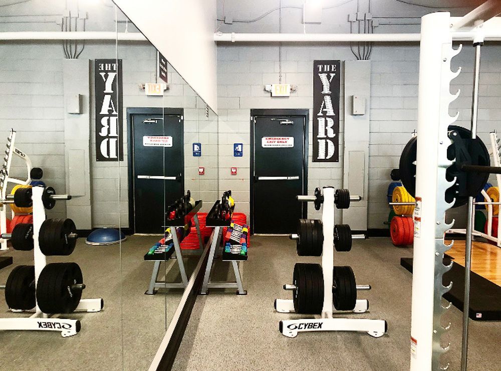 Gym interior with weights, benches, and mirrored wall. The words 
