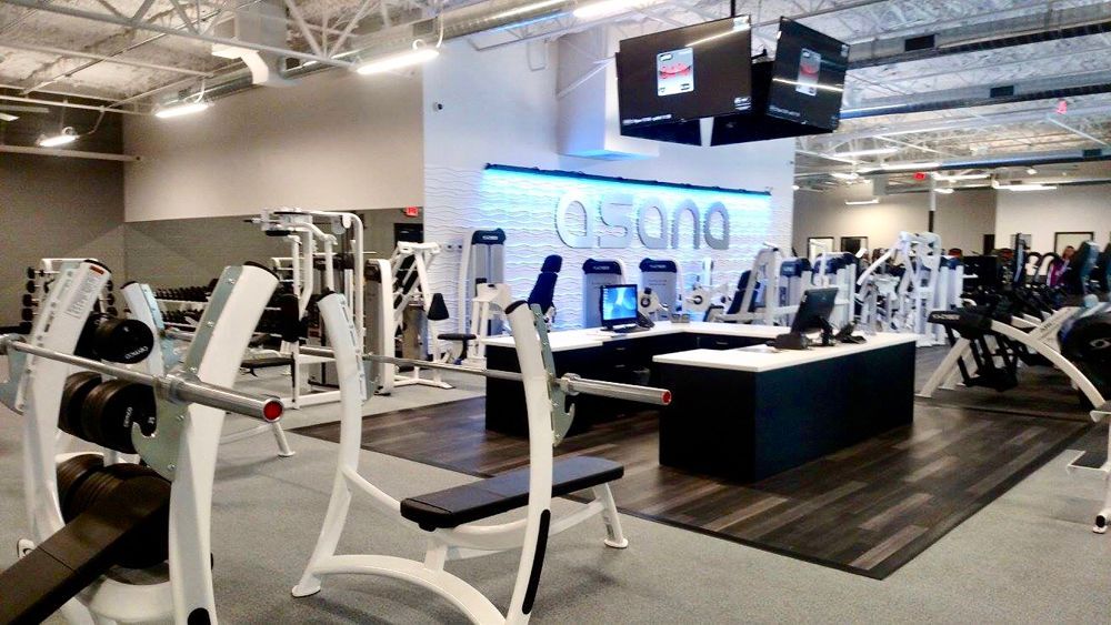 Gym interior with weight machines, free weights, and reception desk. 
