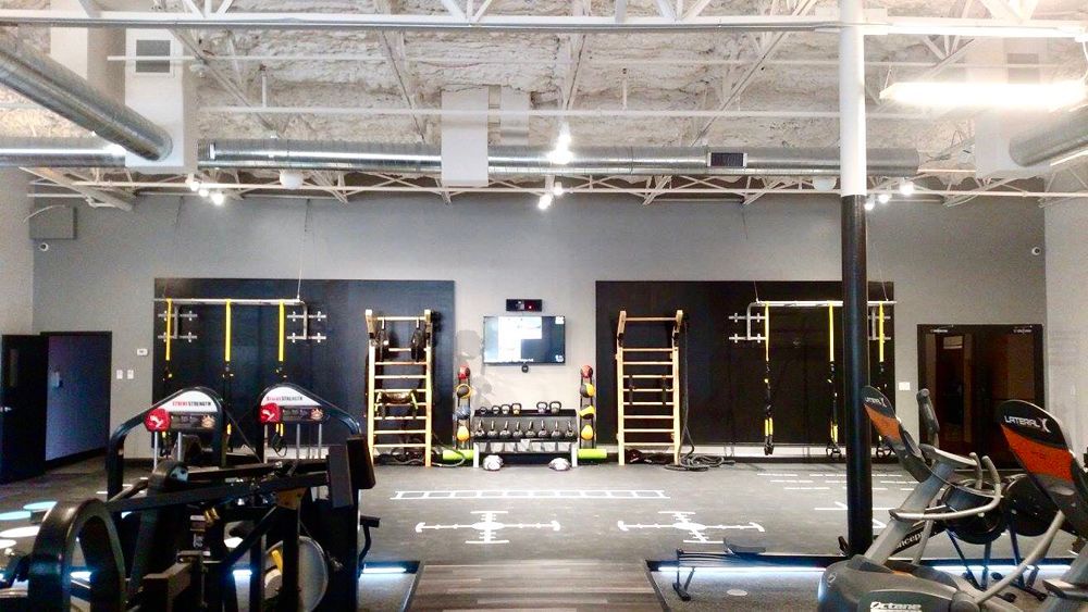 Gym interior with exercise equipment, black and grey walls, and various workout stations.
