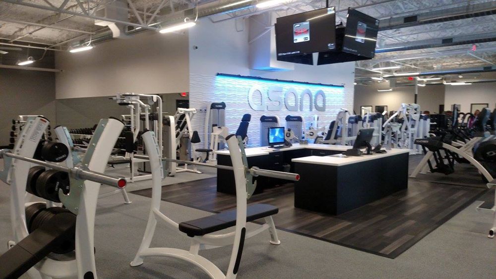 Gym interior with weight machines, benches, and a front desk area.