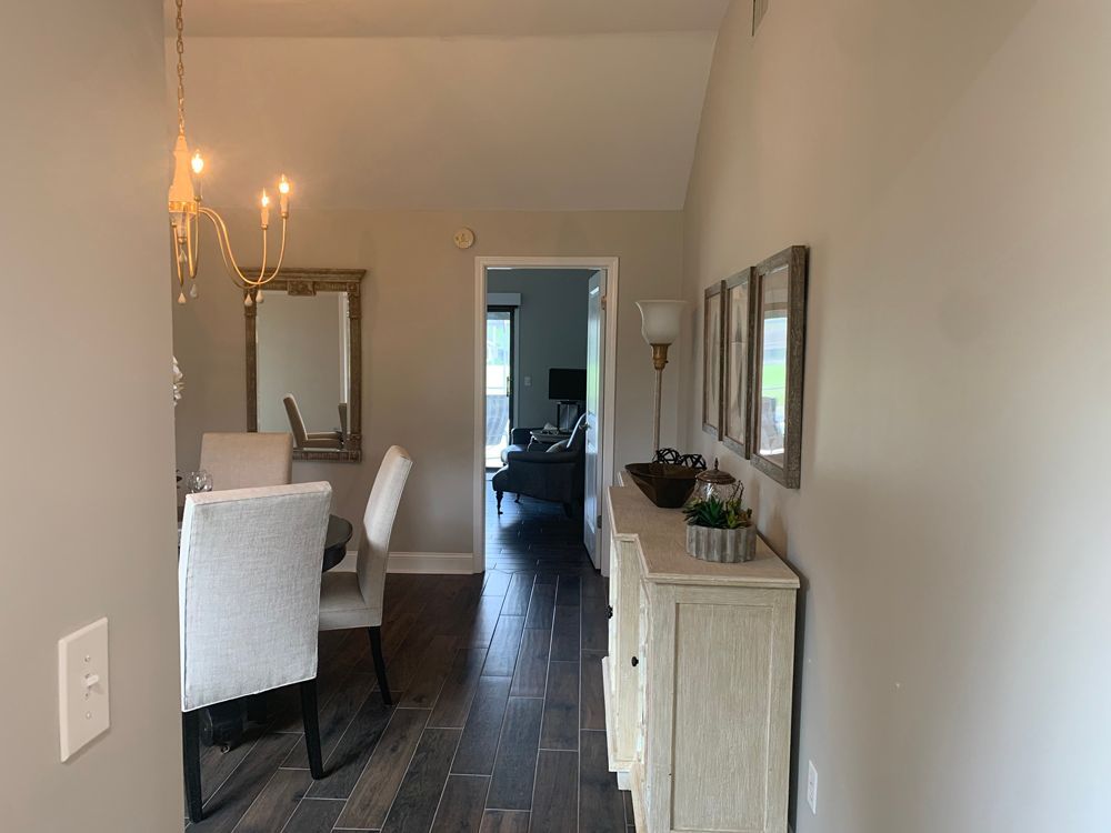 Entryway with dining room on left, hallway with sideboard, and living room in the distance.