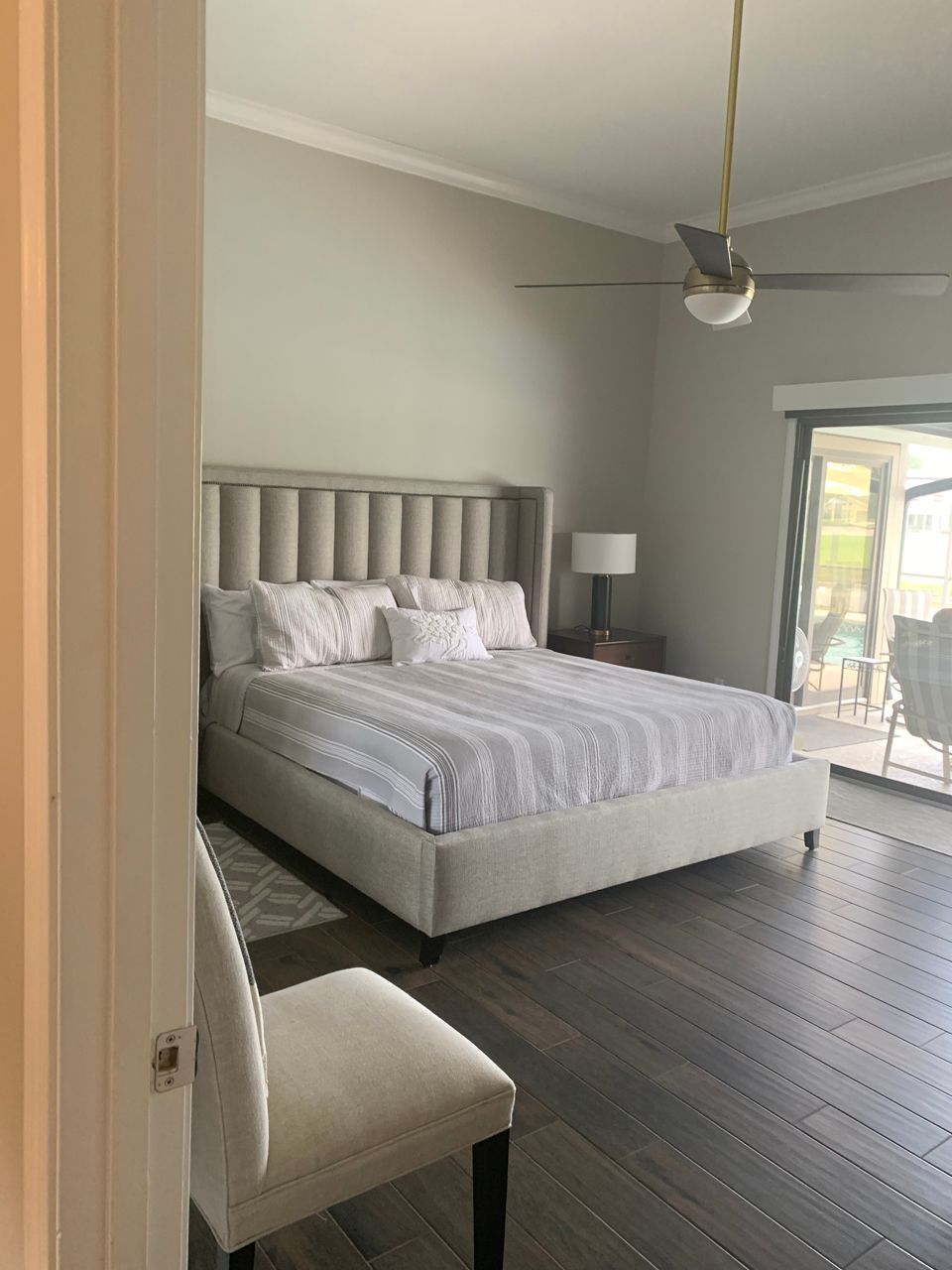 Bedroom with large upholstered bed, hardwood floors, and a view to a patio.