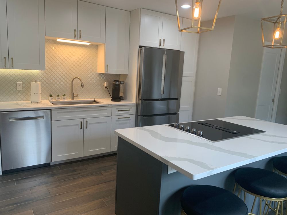 Modern kitchen with white cabinets, stainless steel appliances, and a gray island with seating.