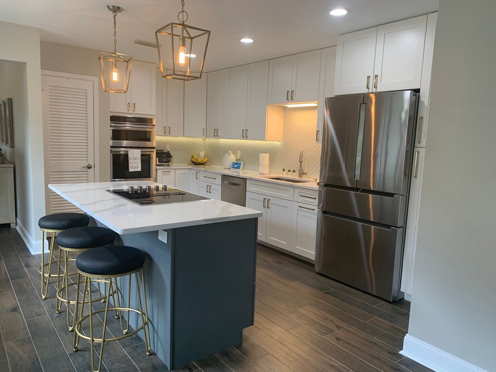 Modern kitchen with white cabinets, stainless steel appliances, blue island, and gold accents.