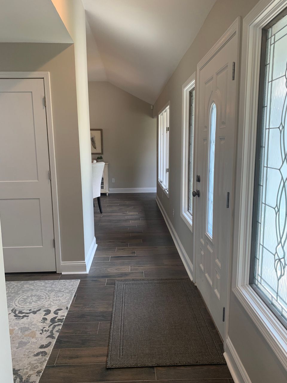 Hallway with hardwood floors, light walls, white doors, and a rug.