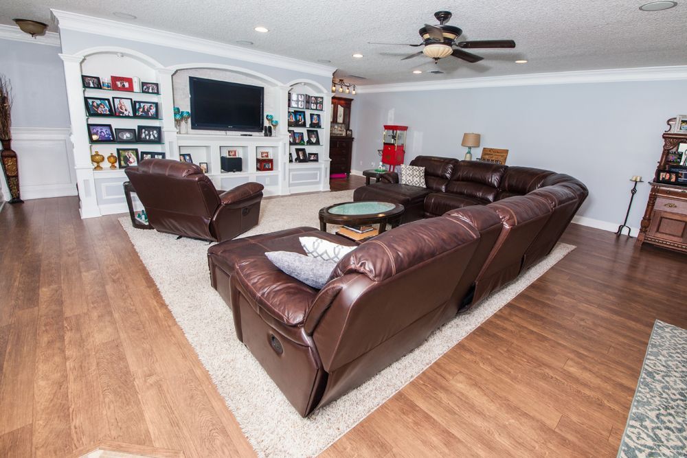 Living room with a large brown leather sectional, TV built-in, recliner, and ceiling fan.