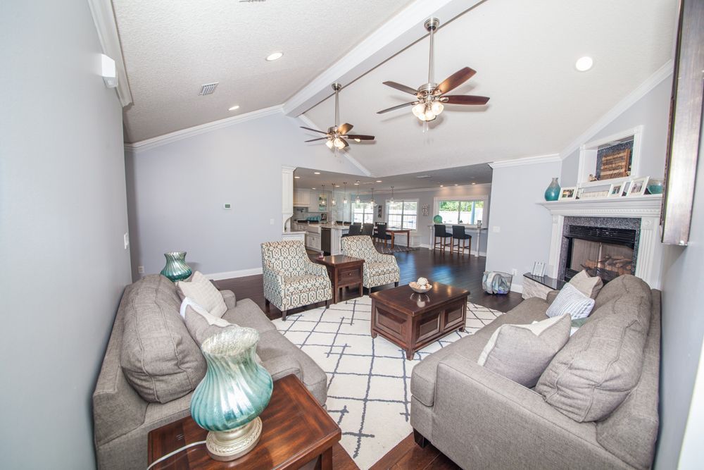 Living room with gray sofas, patterned rug, fireplace, and open kitchen.