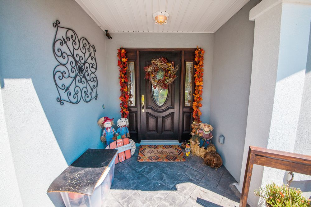 Decorated front porch with fall leaves, wreath, and teddy bears, welcoming guests.