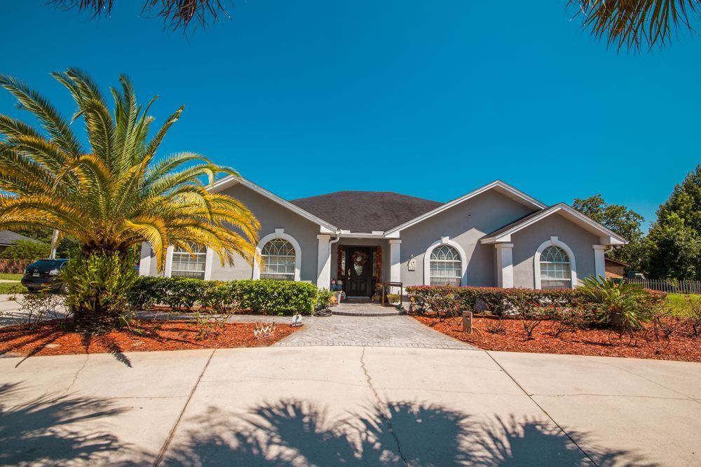 A gray house with white trim, palm tree, and blue sky.