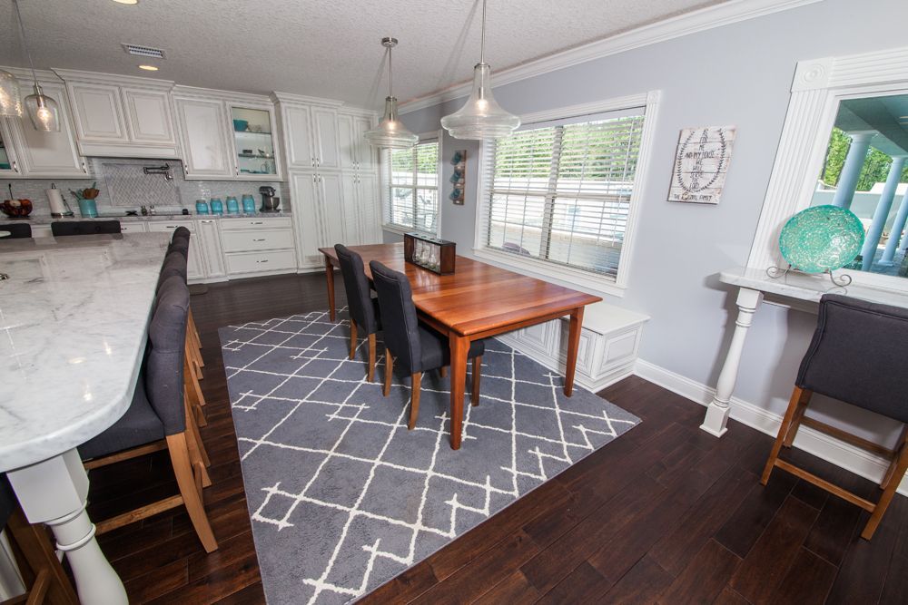 Kitchen with white cabinets, a wooden table, dark chairs, and a gray geometric rug.