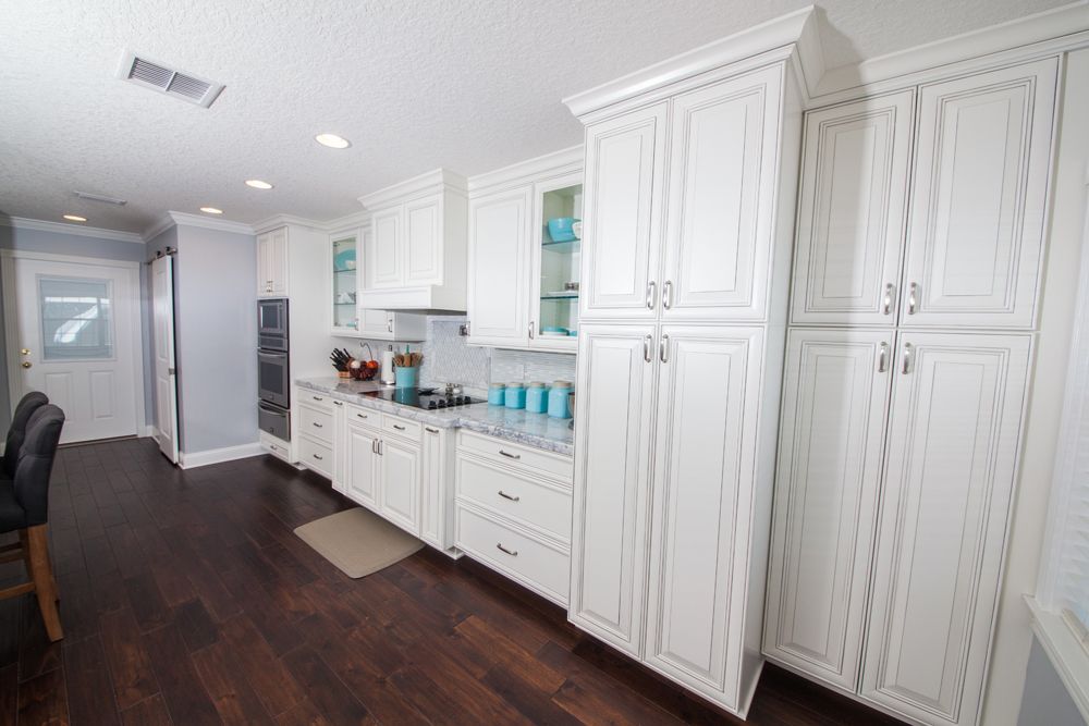 White kitchen with dark wood floors; cabinets, countertops, and appliances.