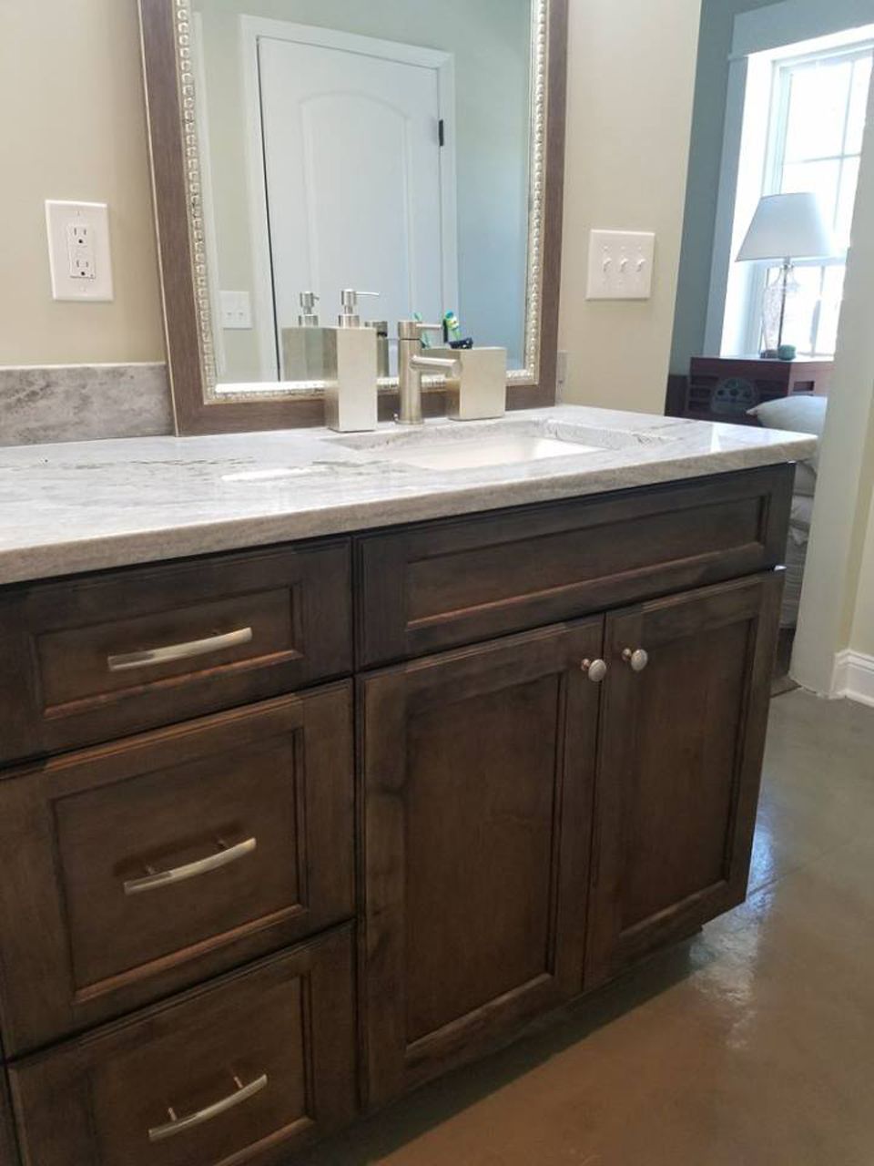 Bathroom vanity with brown cabinets, white countertop, and silver hardware.