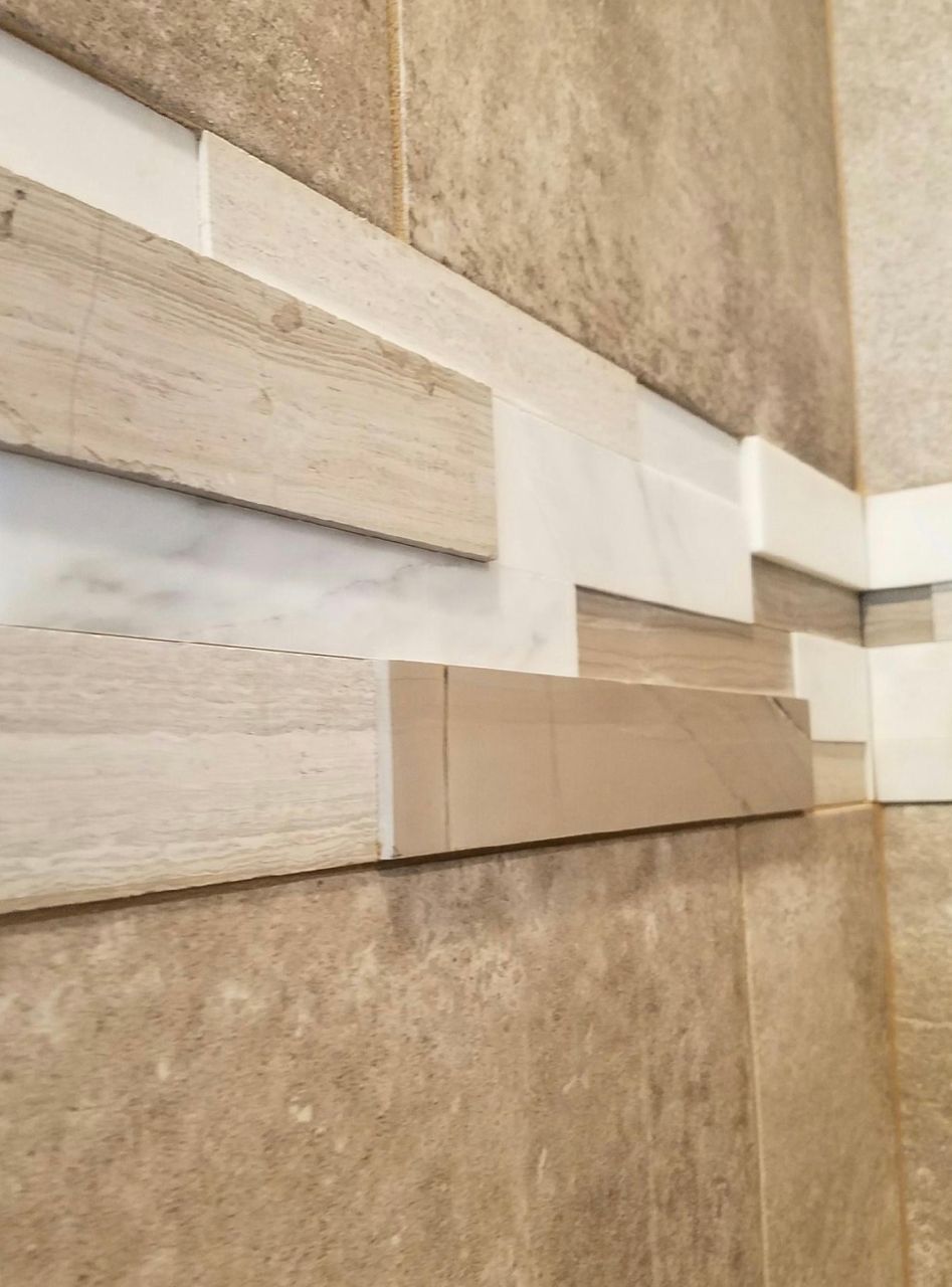 Close-up of bathroom tile: beige, wood-look, and white tiles create a decorative border.