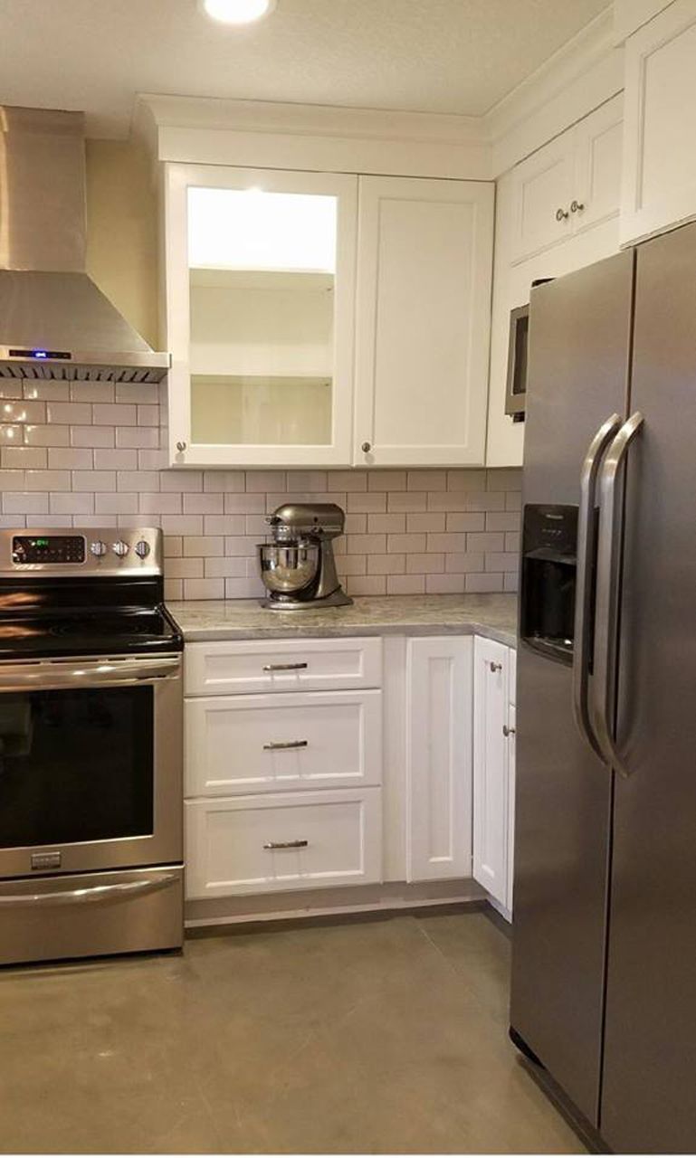 White kitchen with stainless steel appliances, white cabinets, and gray countertops.