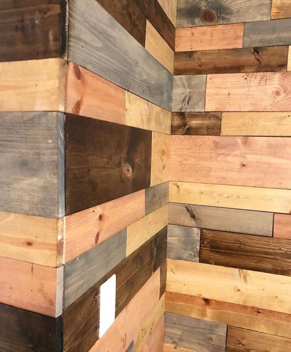 Wood-paneled wall corner with planks in shades of brown, gray, and pink.
