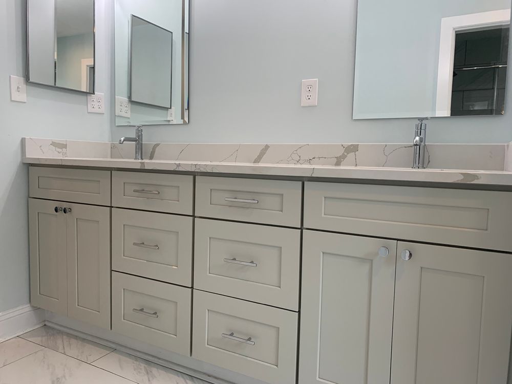 Bathroom vanity with pale blue cabinets, marble countertop, and two rectangular mirrors.
