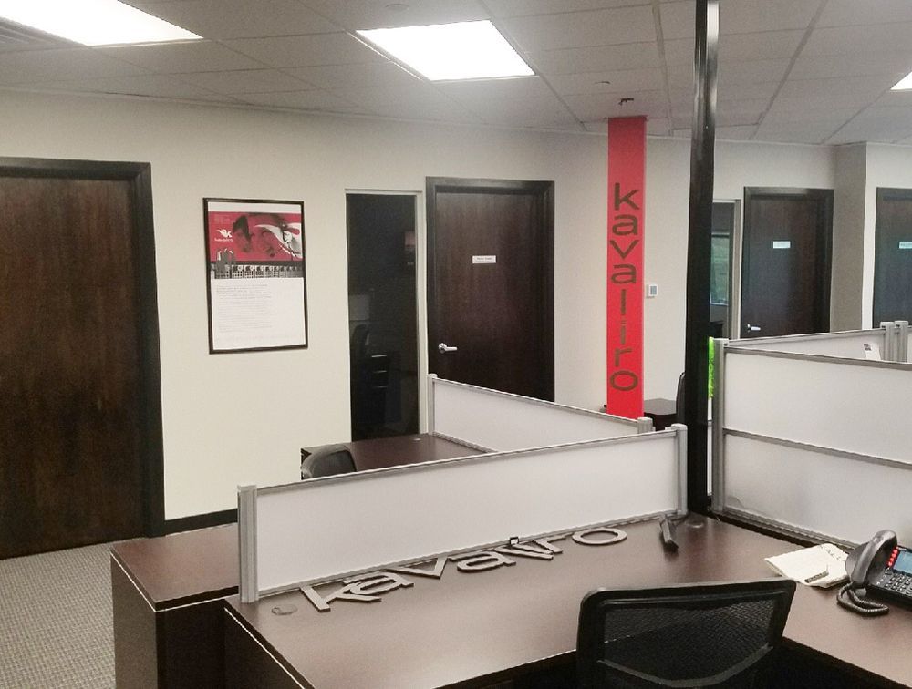 Office cubicles with brown desks, doors, and a red pillar; the word 