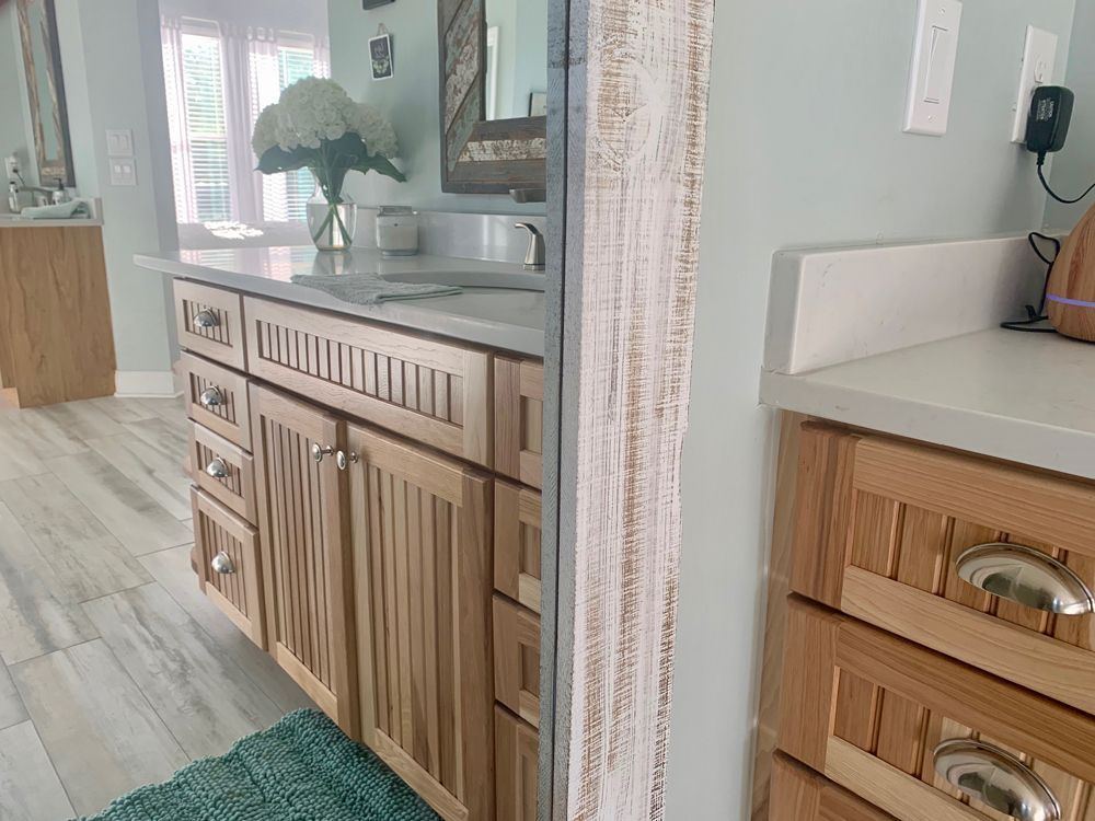 Bathroom with light wood cabinets, gray countertops, and a large mirror.