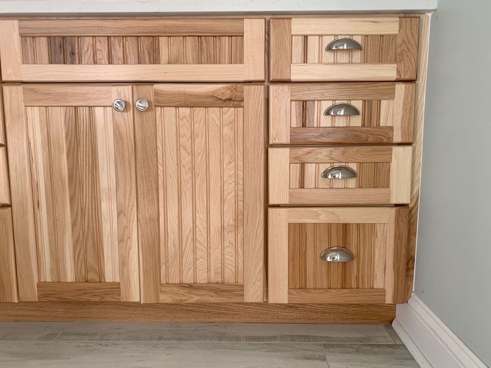 Wooden bathroom vanity with cabinet doors, drawers, and silver hardware.
