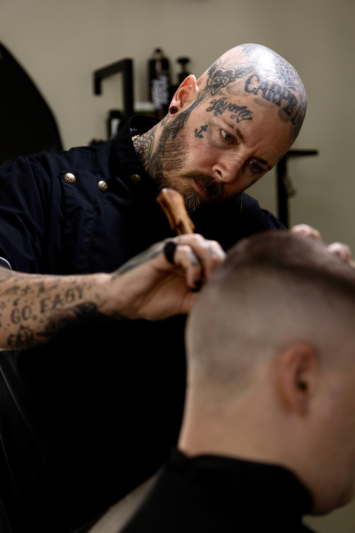 Tattooed barber cutting a client's hair in a barbershop