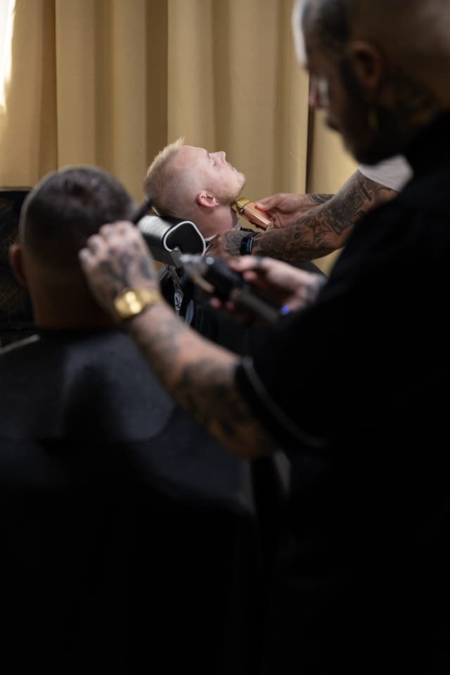 Barber shaving a client’s head in a dimly lit barbershop