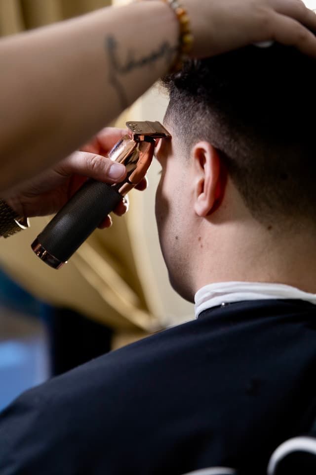 Barber trimming the back of a man’s head with electric clippers