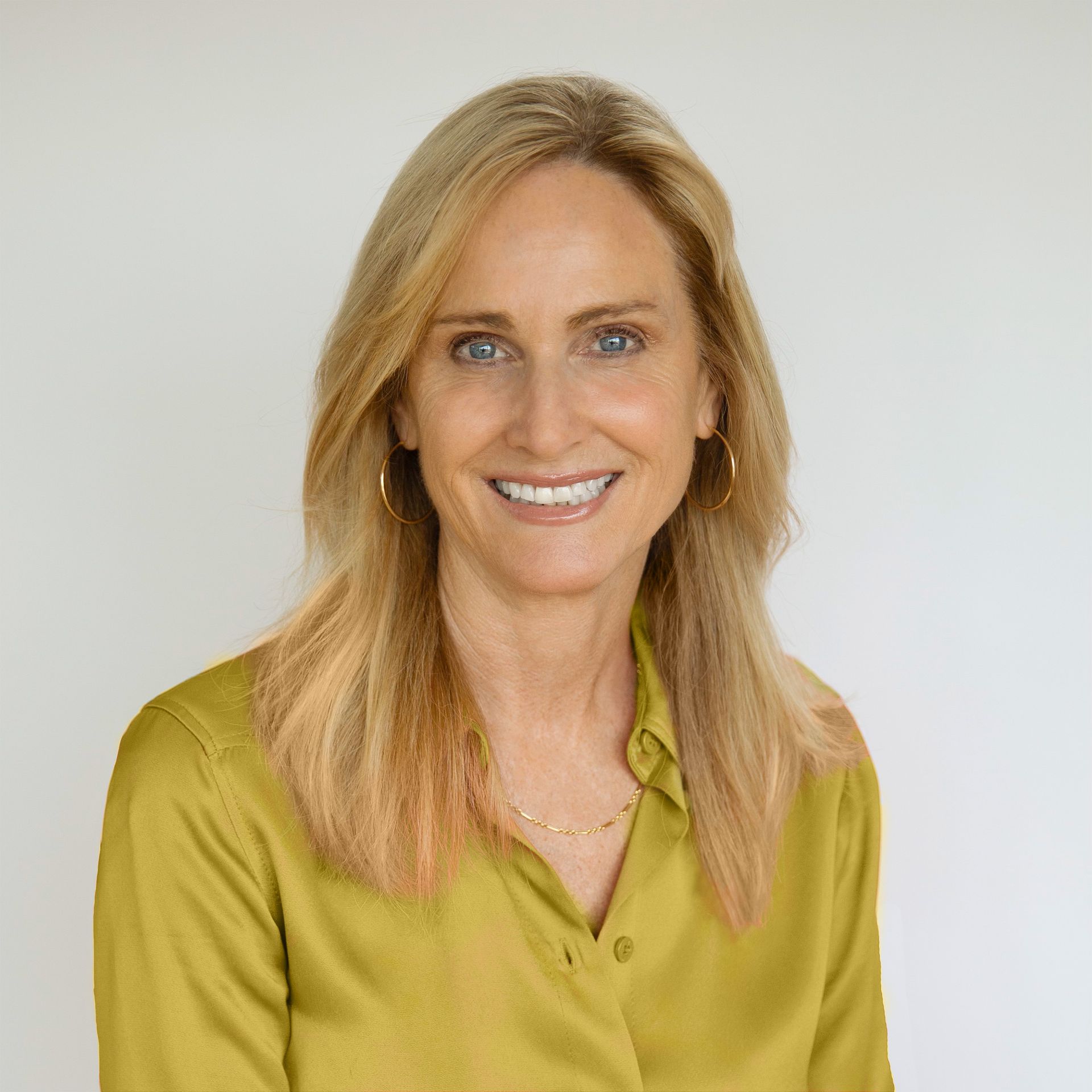 Michelle Vedova Smiling blonde woman in a green blouse against a light gray background