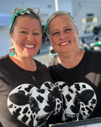 Stacey & Heather, Fat Girls Tallow Two smiling people in black shirts with cow-print pumpkins at an outdoor event