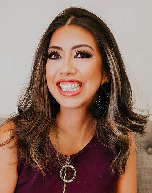 Xiomara Escobar Smiling woman with long dark hair and maroon top, wearing black earrings and a circular pendant necklace.