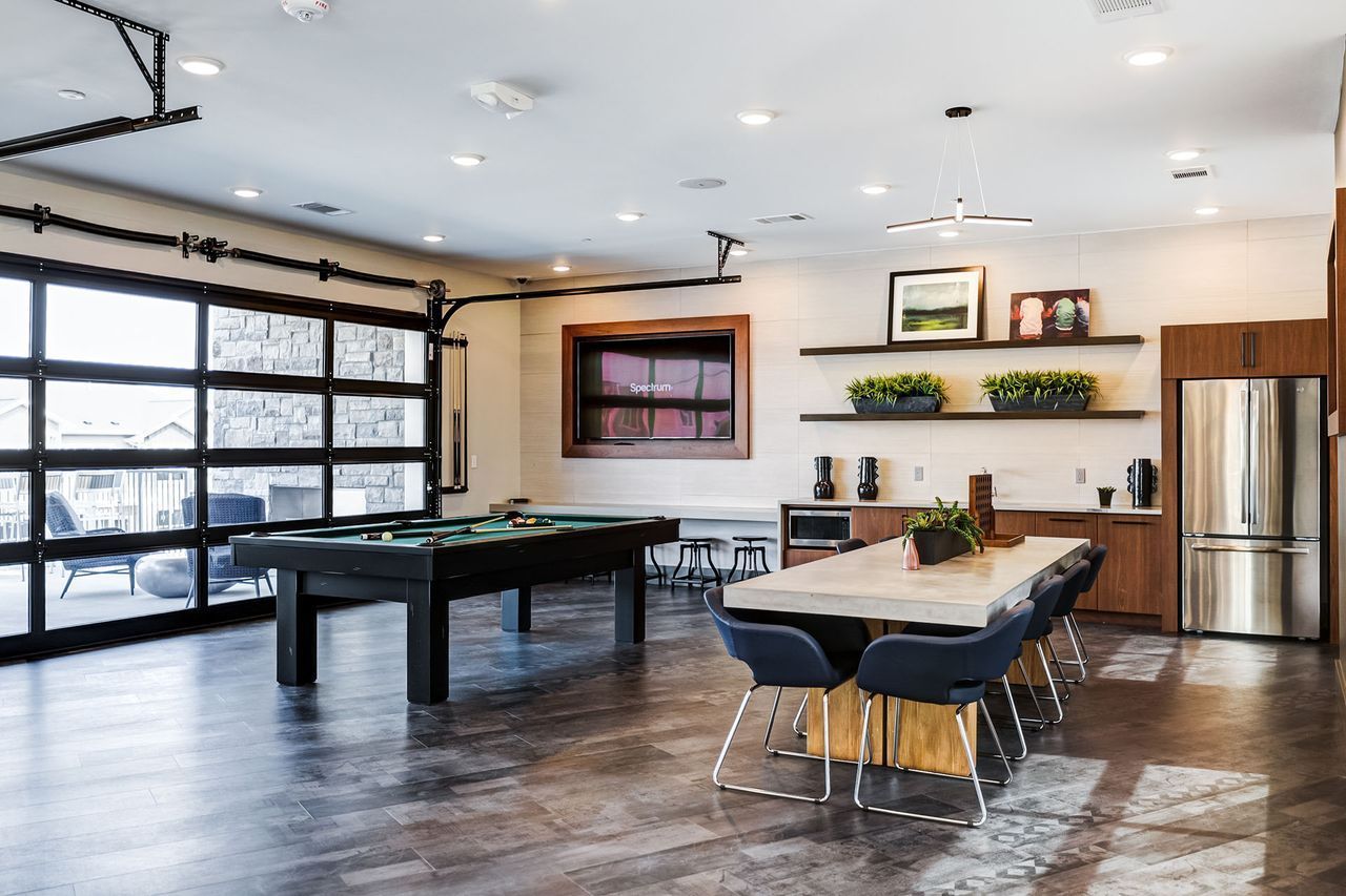 Game room with pool table, large table with chairs, and a stainless steel refrigerator.