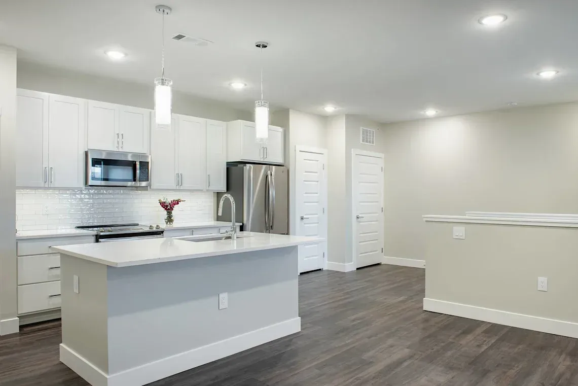 Apartment kitchen with designer lighting, oversized island, and white cabinets at Icon Apartment Homes at Ferguson Farm, offering apartments in Bozeman, MT.