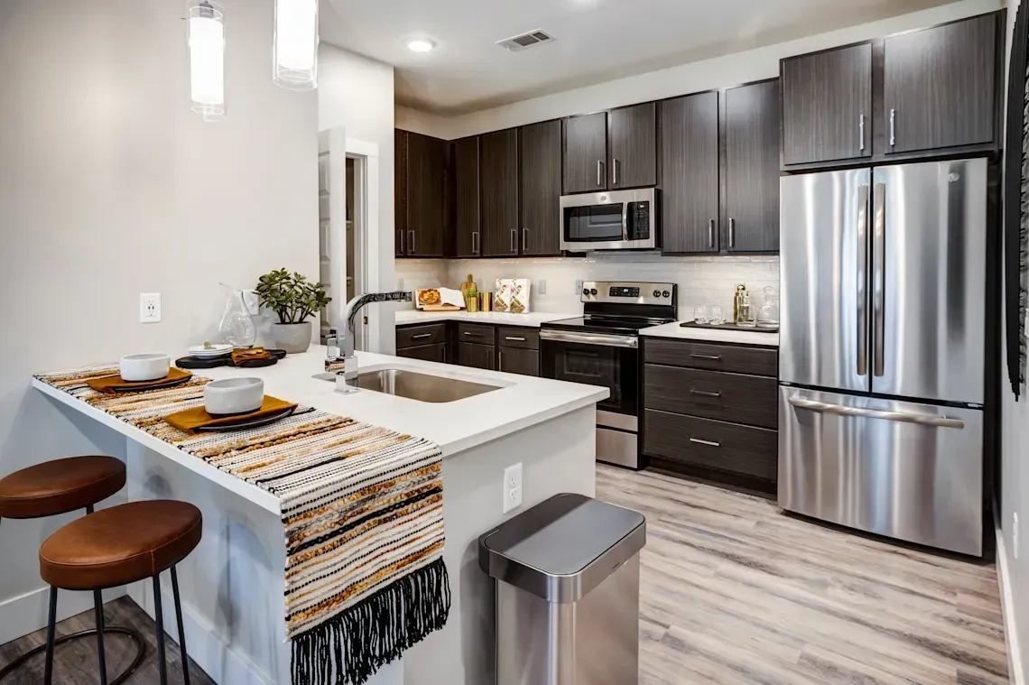 Modern kitchen with dark cabinets and a kitchen island with bar seating at Icon Apartment Homes at Ferguson Farm, offering apartments in Bozeman, MT.