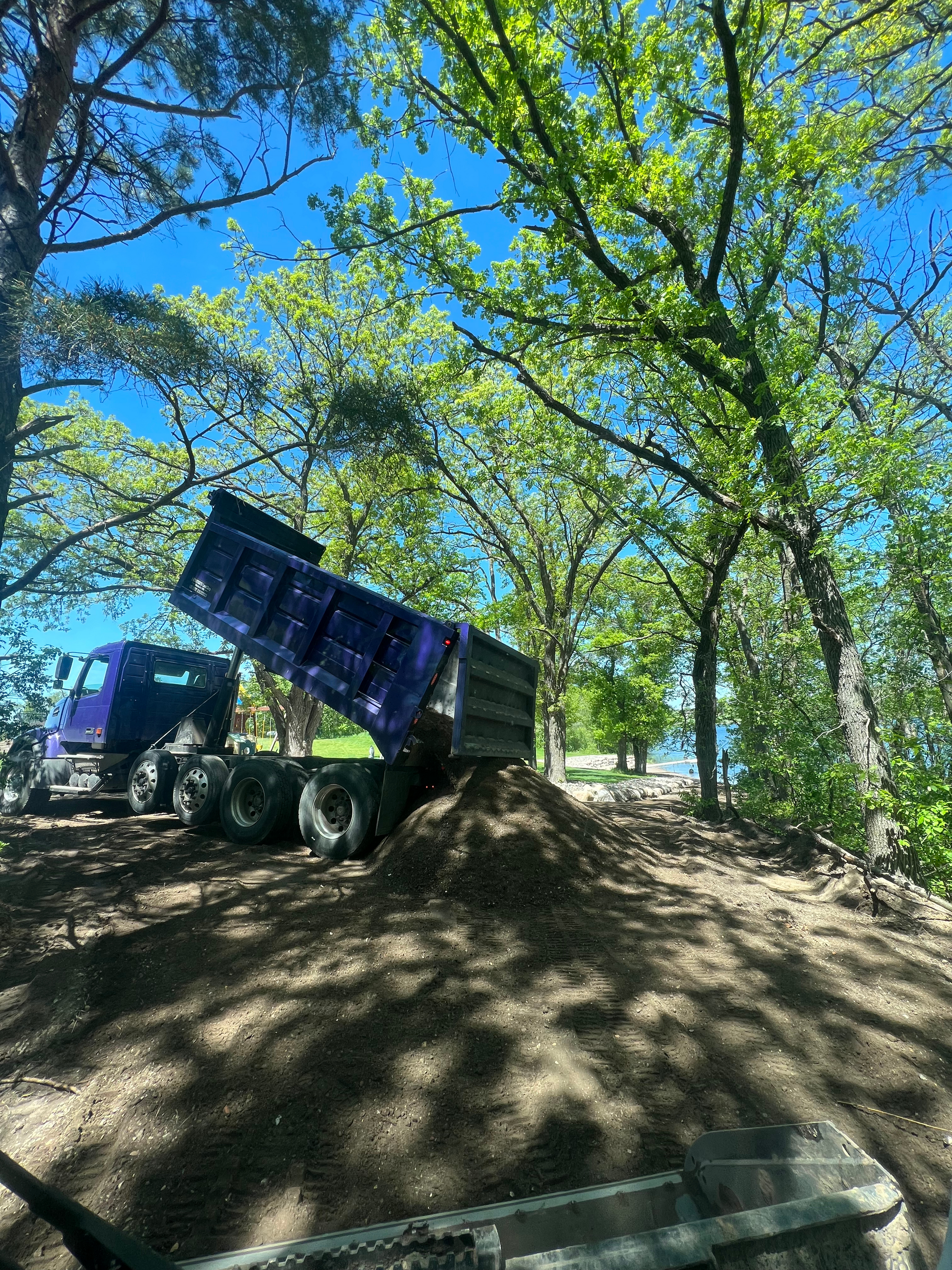 A dump truck is sitting on top of a pile of dirt.