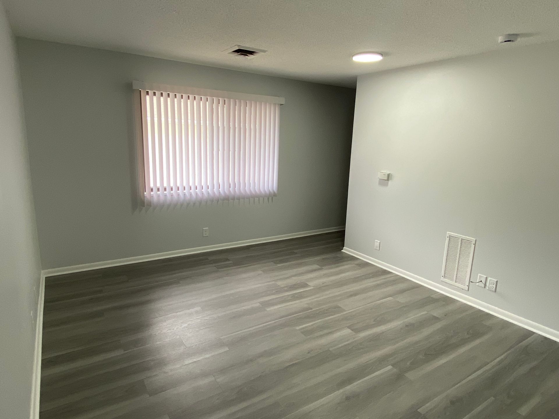 Open closet with white louvered doors and empty shelves in a small room.