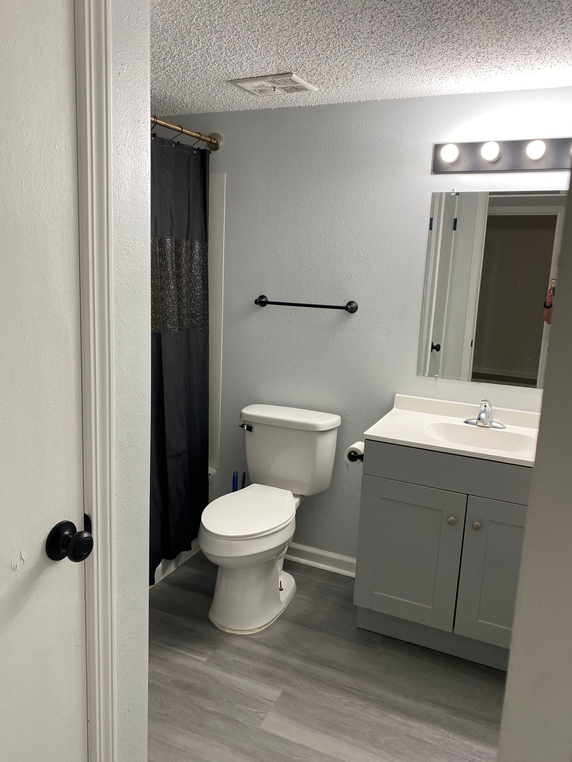 Small bathroom with bathtub, toilet, sink vanity, and gray walls and floor.